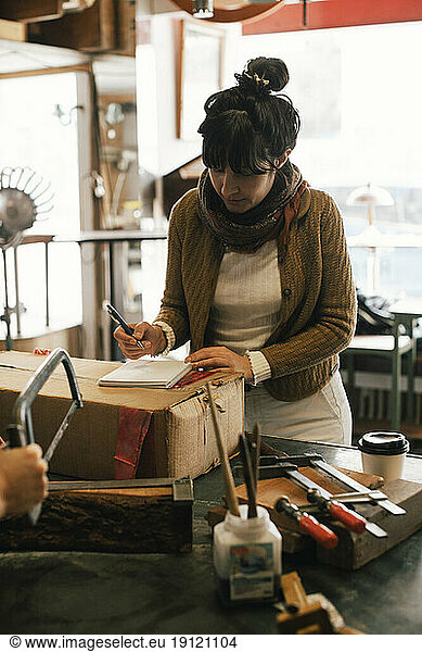 Eine Kundin schreibt in der Werkstatt in ihr Tagebuch