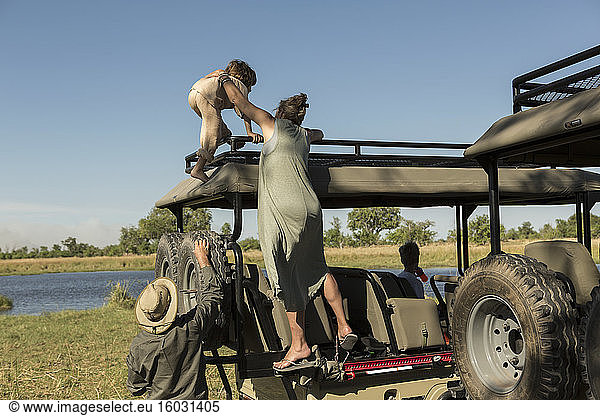 Eine Mutter und ihr Sohn klettern auf die Beobachtungsplattform eines Safari-Fahrzeugs