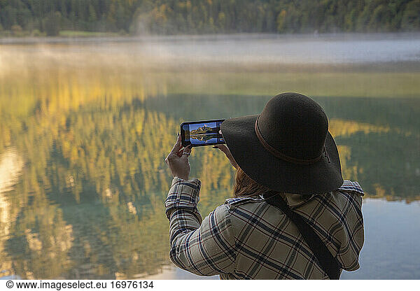 Eine Person  die ein Foto von einem schönen See am Morgen macht.