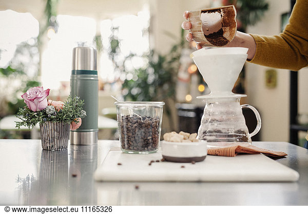 Eine Person  die in einer Küche Filterkaffee zubereitet.