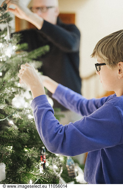 Eine Person  die zu Hause einen Weihnachtsbaum schmückt.