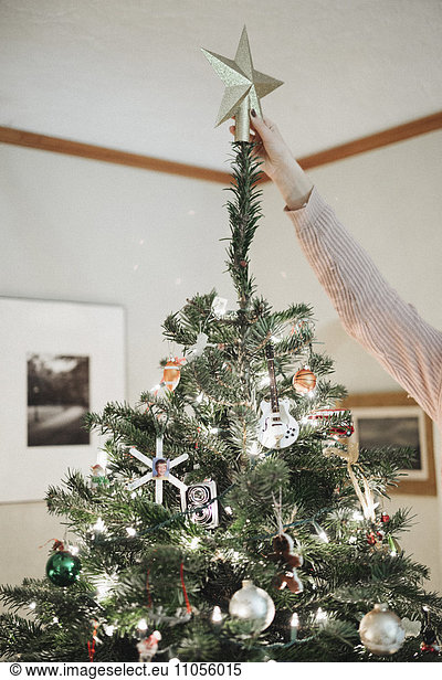 Eine Person  die zu Hause einen Weihnachtsbaum schmückt.