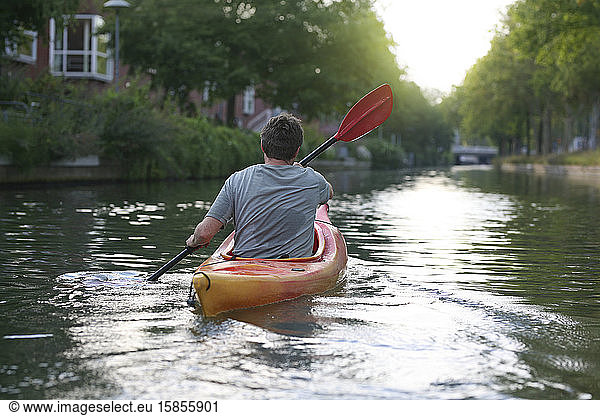 Eine Person paddelt entlang der vorstädtischen Wasserstraßen von Utrecht  Niederlande