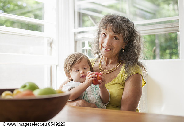 Eine reife Frau  ein Großelternteil  der ein 1 Jahr altes Kind  ihre Enkelin  wiegt.