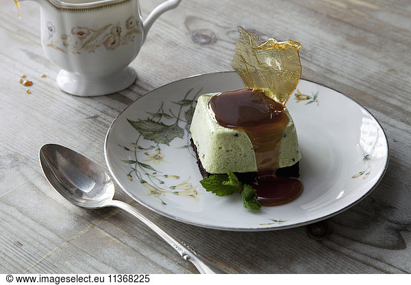 Eine süße Dessertschale mit Zuckerwerk und Sauce auf einem Porzellanteller  mit Löffel und Tasse.