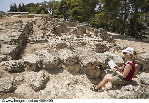 Eine Touristin sitzt inmitten der Ausgrabungsstätte der minoischen Paläste von Festos  Insel Kreta  Griechenland