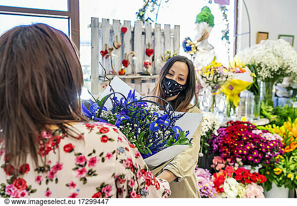 eine unternehmungslustige Frau überreicht ihrem Kunden einen Blumenstrauß