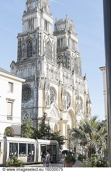 Eine vorbeifahrende Straßenbahn spiegelt die starken diagonalen Linien der verschiedenen architektonischen Register der schönen Kathedrale von Orléans mit ihrem eleganten filigranen steinernen Maßwerk  den üppigen Bögen und den mittelalterlichen Rosettenfenstern wider.
