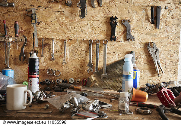 Eine Werkbank und Werkzeugtafel in einer Fahrradwerkstatt. Kaffeetasse  Handwerkzeuge  Schrauben und Muttern und Schraubenschlüssel.