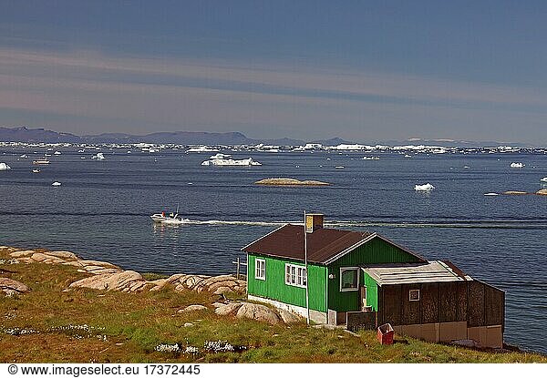 Einfaches Wohnhaus am Rande einer mit Eisbergen bedeckten Bucht  Ilulissat  Arktis  Diskobucht  Grönland  Dänemark  Nordamerika