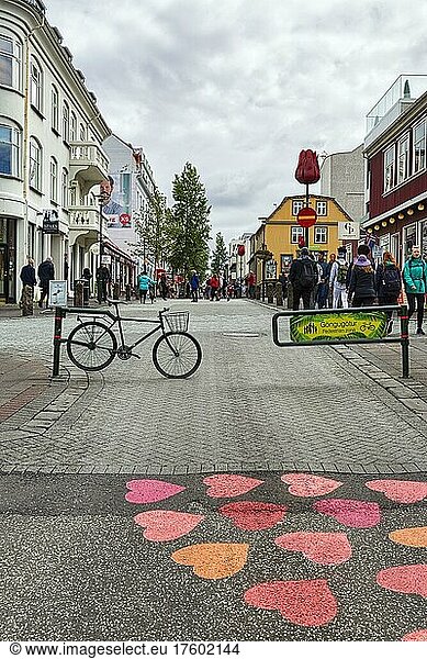 Eingang zur Fußgängerzone Göngugötur  Fahrrad als Absperrung  rote und orangefarbene Herzen auf Asphalt  Straßenkunst  Reykjavik  Island  Europa