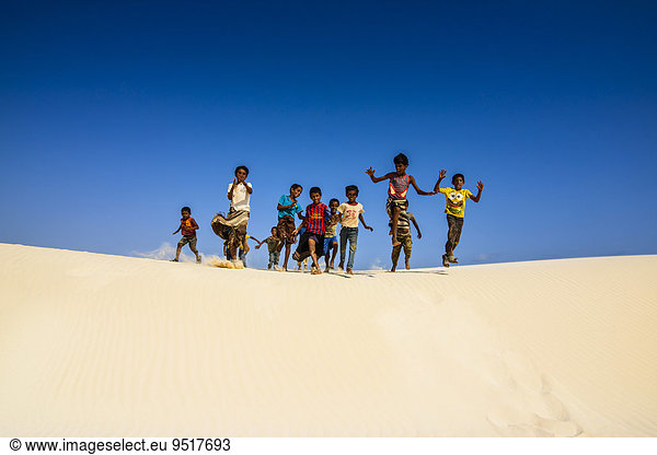 Einheimische Jungen aus Sokotra rennen in den Sanddünen an der Südküste der Insel Sokotra  Jemen  Asien