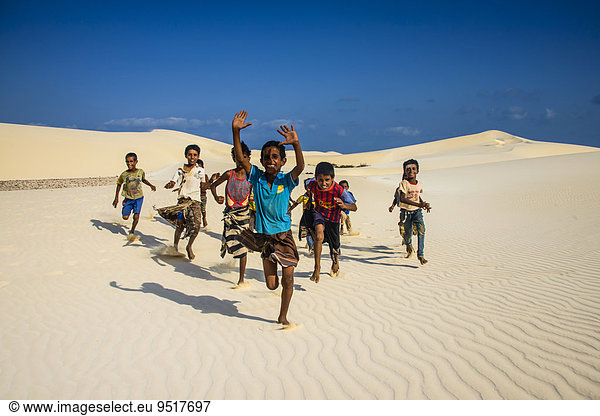 Einheimische Jungen aus Sokotra rennen in den Sanddünen an der Südküste der Insel Sokotra  Jemen  Asien