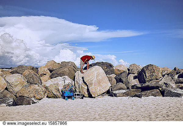 Einheimischer Fischer klettert mit Angelausrüstung auf den Steg im Sand