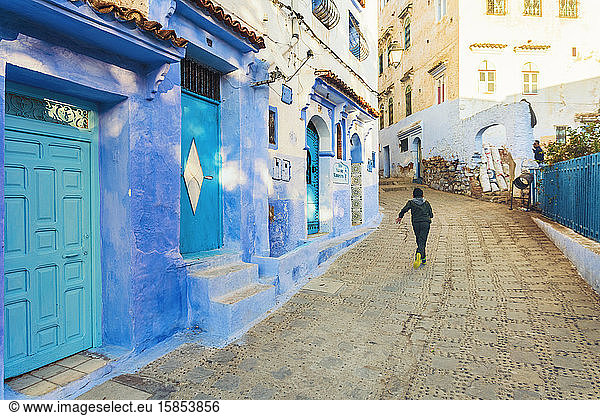 Einheimischer Junge rennt in der Straße des blauen Dorfes Chefchaouen