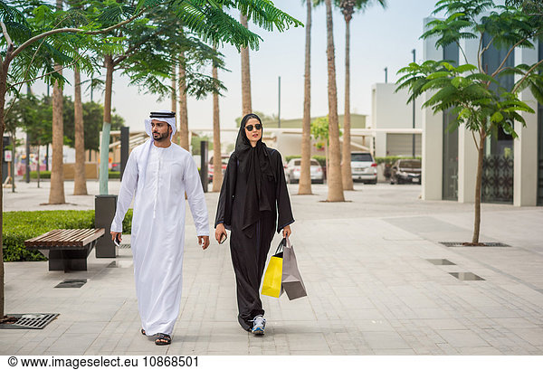 Einkaufspaar aus dem Nahen Osten in traditioneller Kleidung auf der Straße  Dubai  Vereinigte Arabische Emirate