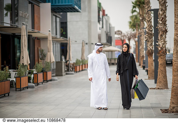 Einkaufspaar aus dem Nahen Osten trägt traditionelle Kleidung mit Einkaufstaschen  Dubai  Vereinigte Arabische Emirate