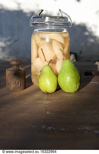 Einmachglas mit geschnittenen Birnen  zwei frische Birnen und altes Gewicht