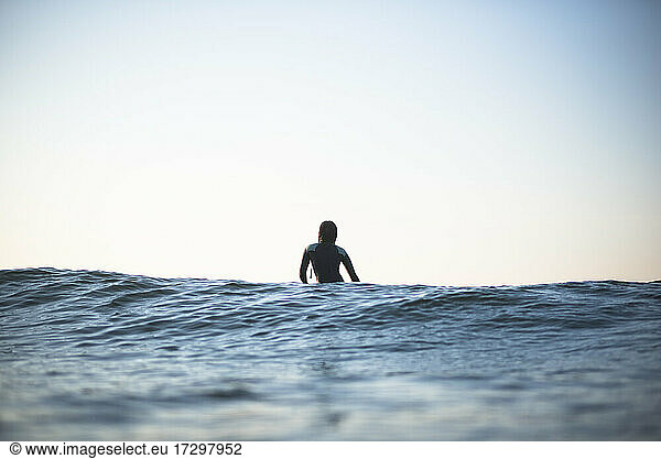Einzelne asiatische Frau in der Sommer-Surf-Lineup in der Morgendämmerung