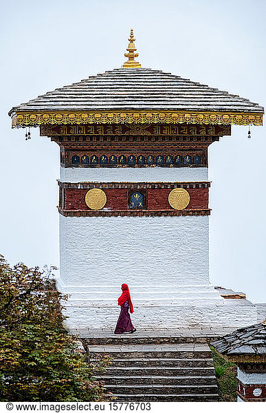 Einzelne Nonne geht am Dochula-Pass an einem Tempel vorbei  Bhutan  Asien
