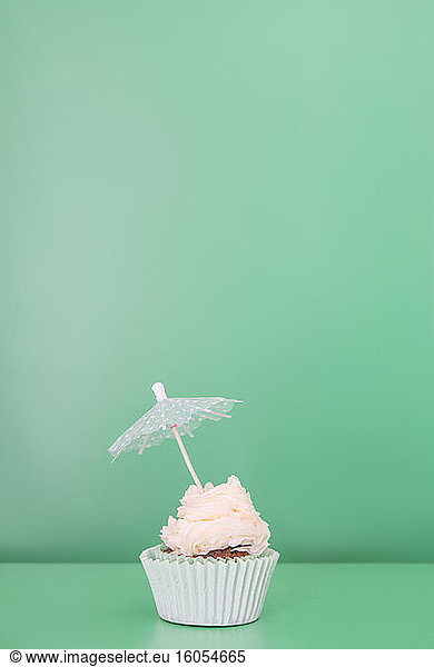 Einzelner Cupcake dekoriert mit Getränkeschirm