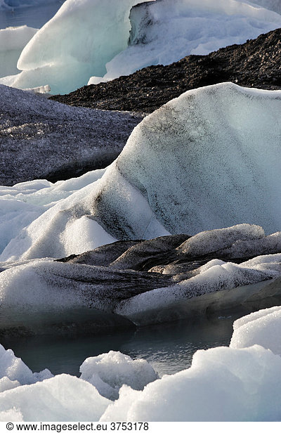 Eisberge deren unterschiedliche Färbung bis hin zu schwarz von Vulkanasche herrührt Gletschersee Jökulsarlon Südküste Island