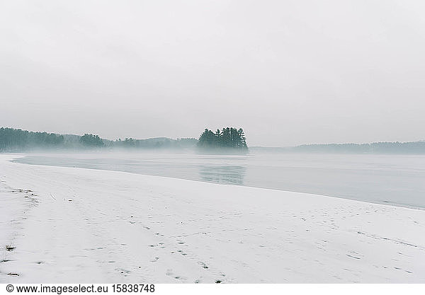 Eisiger See bei Regen und Nebel.