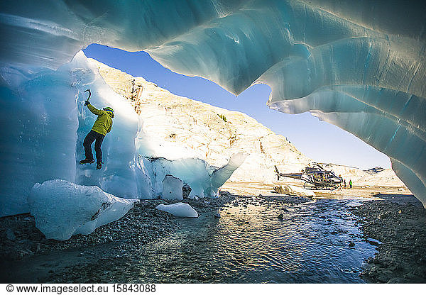 Eiskletterer  der auf Gletschereis neben dem Hubschrauber klettert.