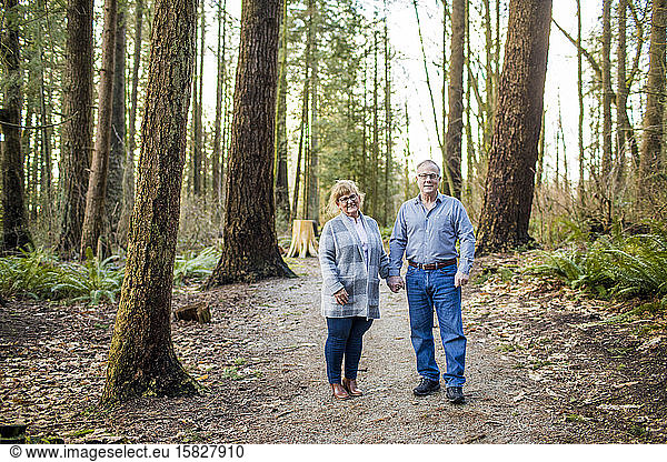 Elderly couple holding hands in the forest.