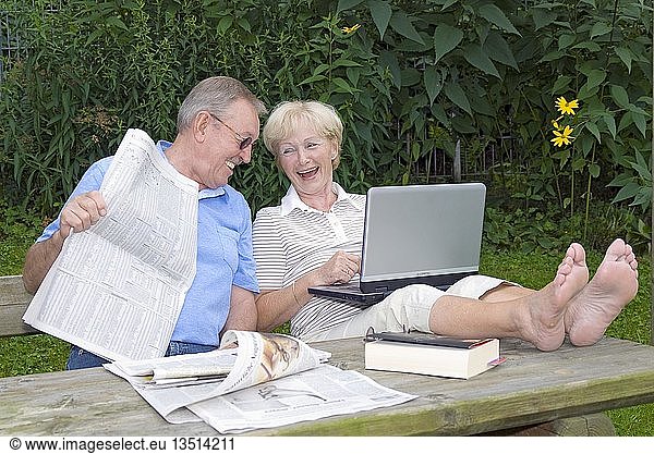 Elderly couple with laptop and newspaper