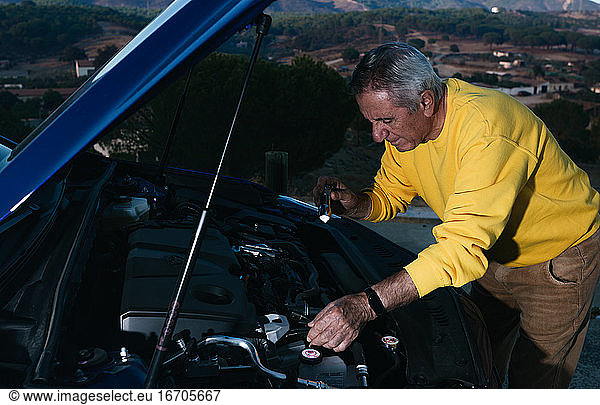 Elderly traveler with flashlight opening the trunk of the vehicle