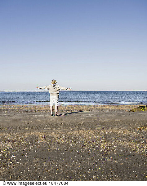 Elderly woman admiring sea at beach on sunny day