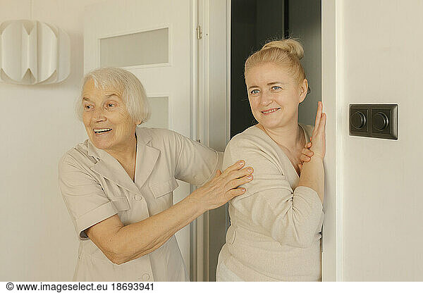 Elderly woman standing by daughter near doorway at home