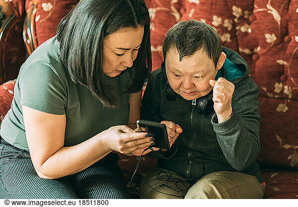 elderly woman with Down syndrome  asian assistant helps to use phone