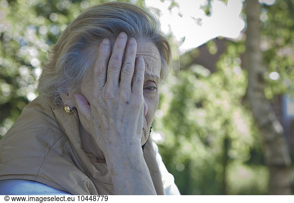 elderly woman with hand on the face