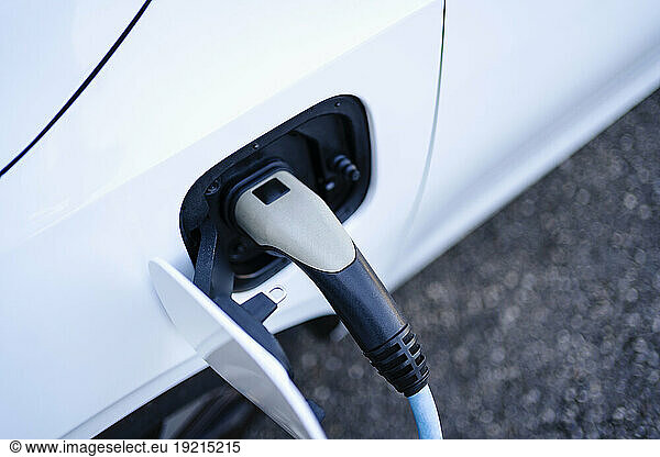 Electric car charging with plug at station