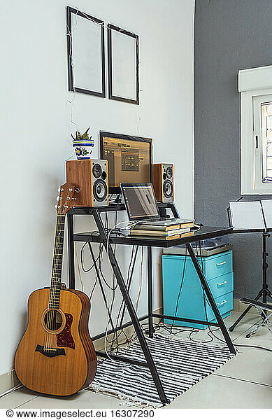 Electric guitar by table with laptop and books at home