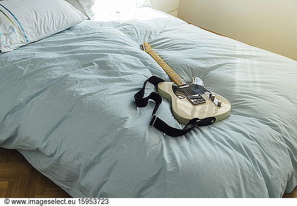 Electric guitar lying on bed