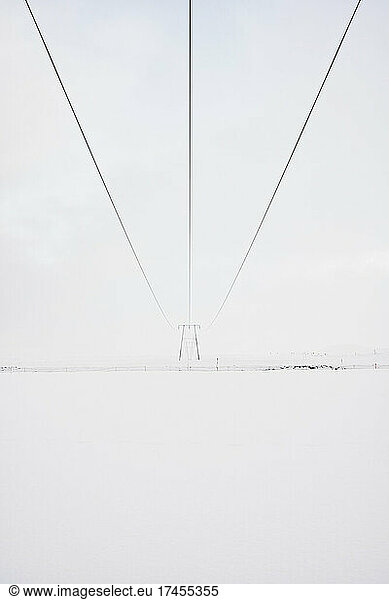 Electric tower on snowy land in countryside