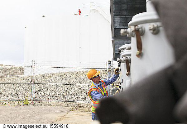 Electrical engineer examining spare power transformers with fuel tank storage in background