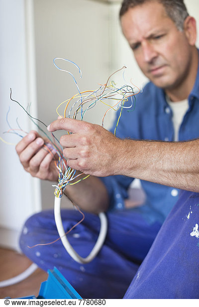 Electrician examining wires in kitchen