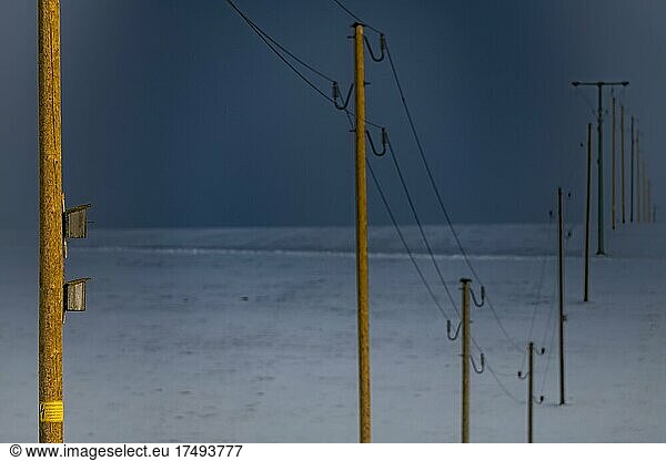 Electricity pylons in winter landscape against dramatic sky  Obergünzburg  Ostallgäu  Bavaria  Germany  Europe
