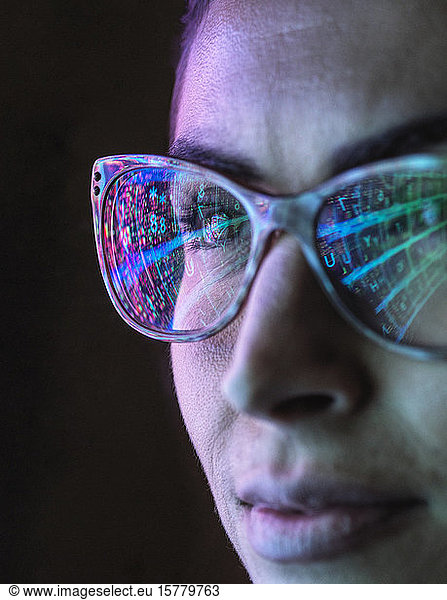 Electronic circuit board on computer monitor reflecting in glasses of a female engineer.