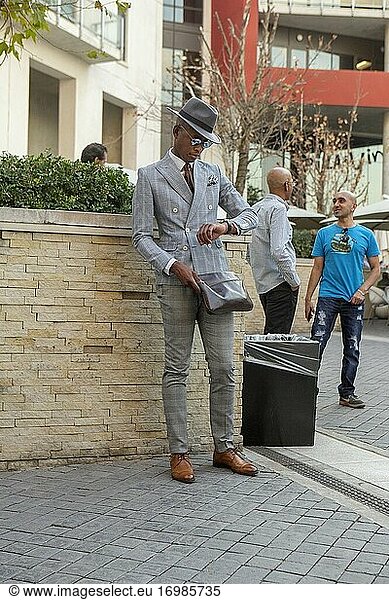 Elegant gekleideter afrikanischer Mann schaut auf seine Uhr in Melrose Arch  Johannesburg  Südafrika