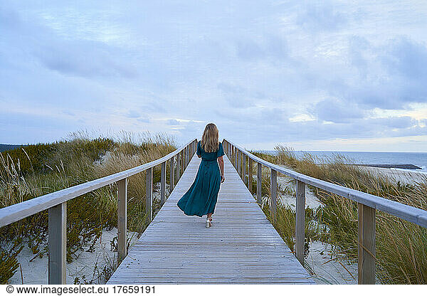elegant girl walking along a walkway in front of the sea