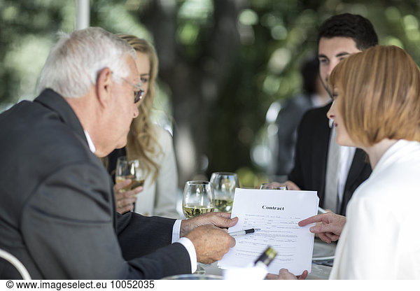 Elegant people at outside restaurant discussing a contract