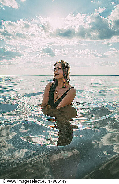 Elegant woman sits in the water. The concept of unity with nature.