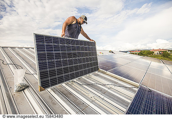 Elektriker installiert Sonnenkollektoren auf dem Dach.