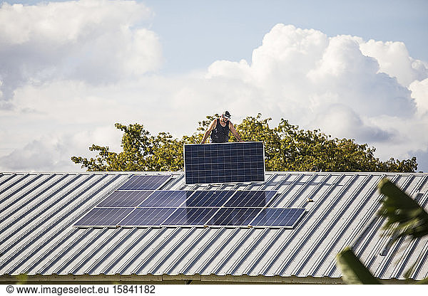 Elektriker trägt Sonnenkollektor auf dem Dach.