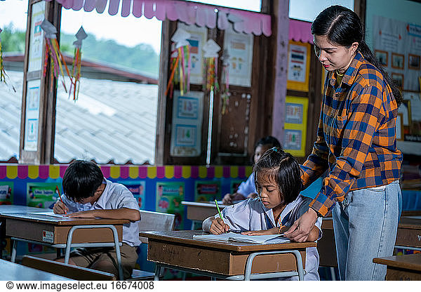 Elementary school teacher helping student in classroom Education